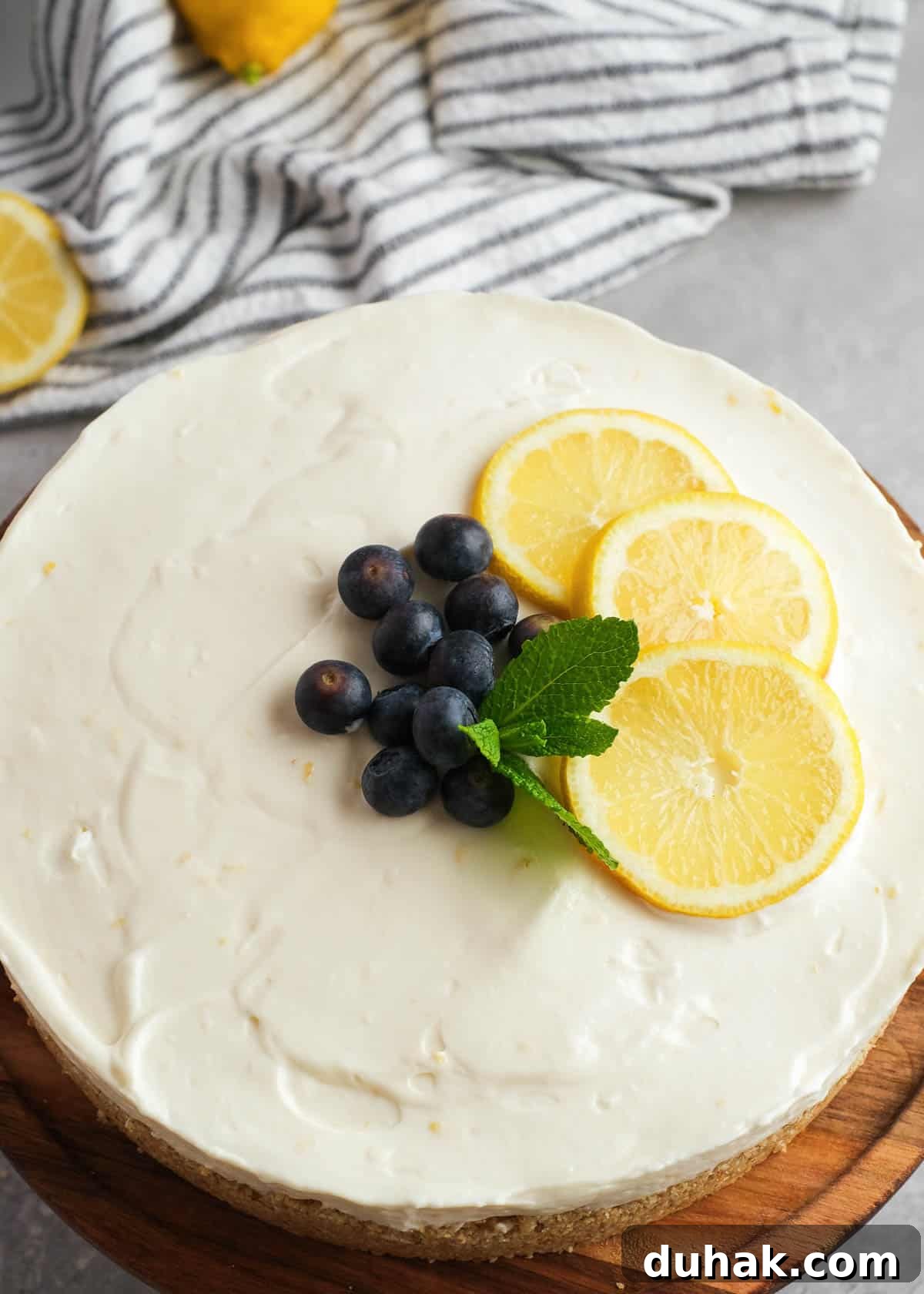 Lemon Cheesecake Recipe with Zesty Citrus Cream Filling 12 closeup view of creamy no-bake lemon cheesecake garnished with blueberries and lemons