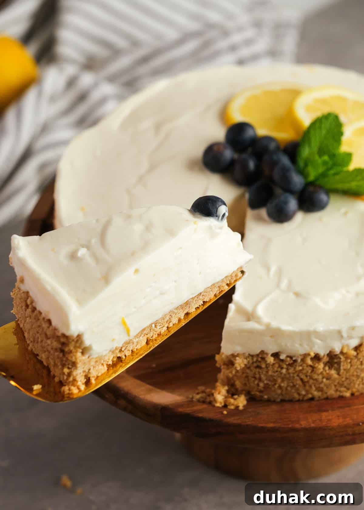 Lemon Cheesecake Recipe with Zesty Citrus Cream Filling 13 a serving spatula grabbing a slice of easy lemon cheesecake topped with blueberries