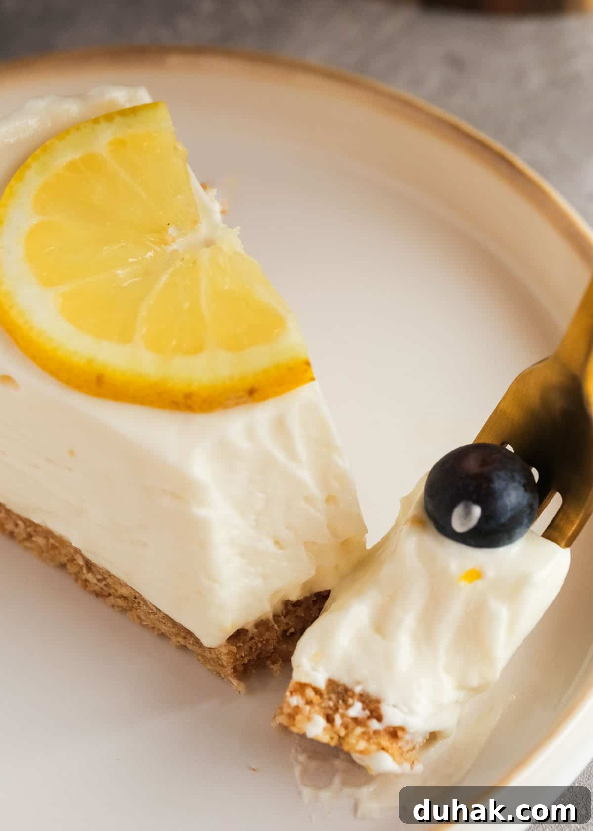 Lemon Cheesecake Recipe with Zesty Citrus Cream Filling 16 a fork taking a creamy bite of the luscious lemon cheesecake