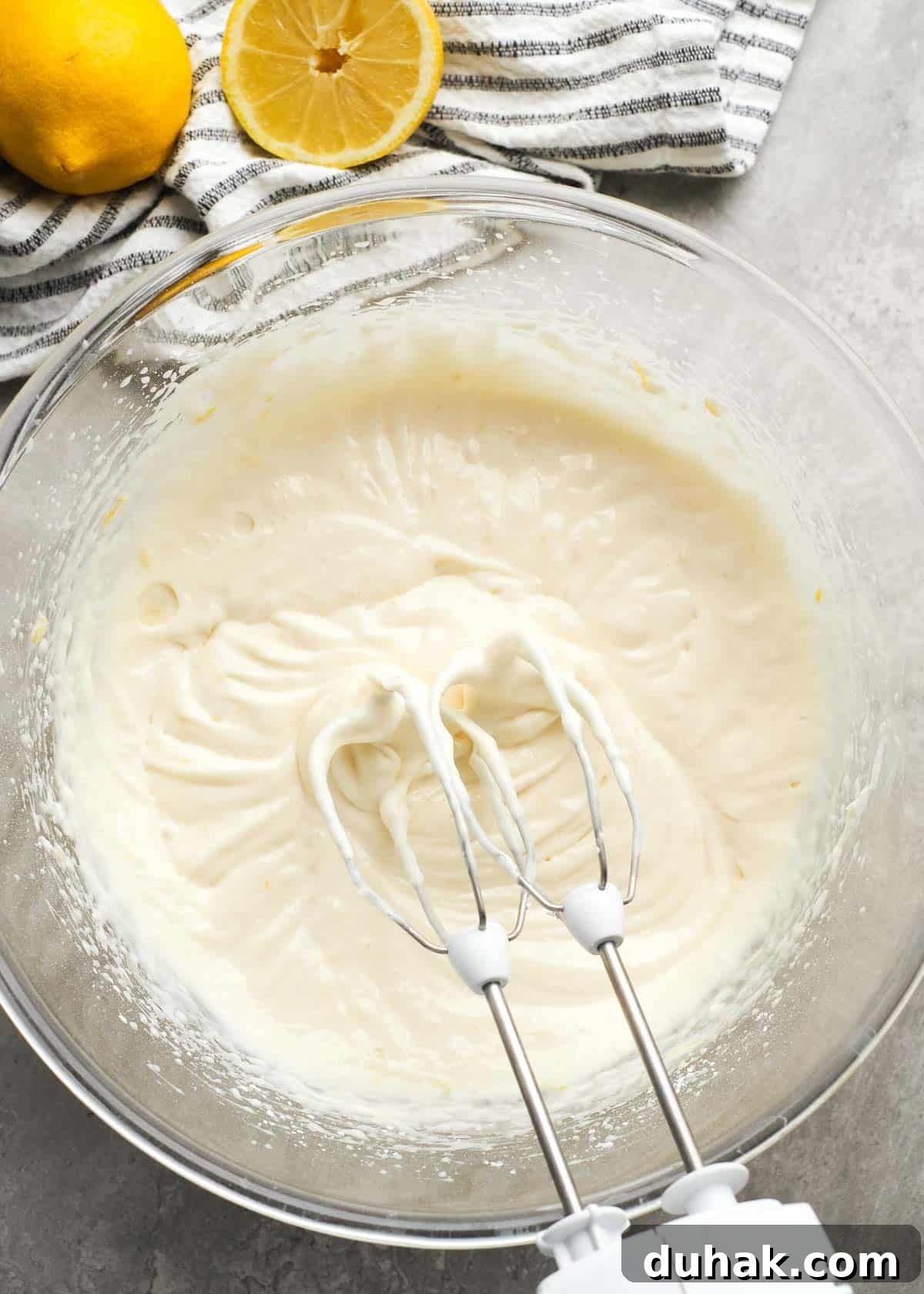 Lemon Cheesecake Recipe with Zesty Citrus Cream Filling 6 cream cheese, lemon juice, lemon zest, vanilla extract, powdered sugar, and lemon extract beaten in a glass bowl with an electric mixer