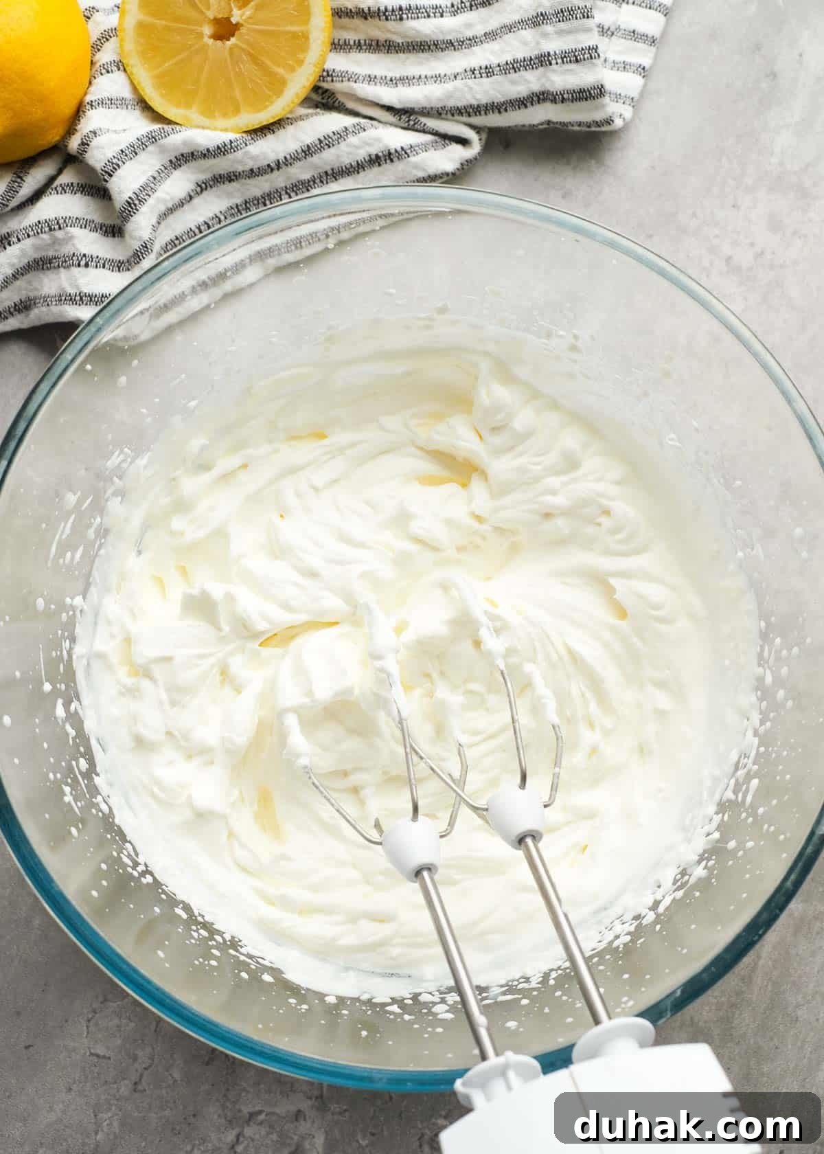 Lemon Cheesecake Recipe with Zesty Citrus Cream Filling 7 heavy cream beaten into whipped cream with stiff peaks in a glass bowl using an electric mixer