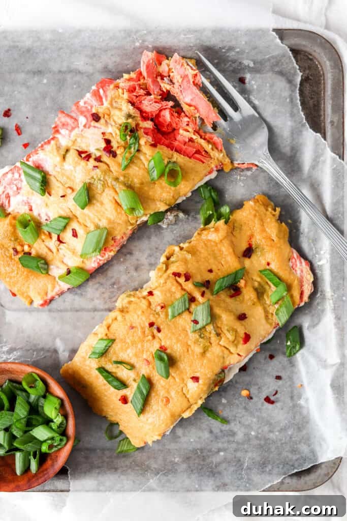 herb crusted salmon with a silver fork garnished with green onions