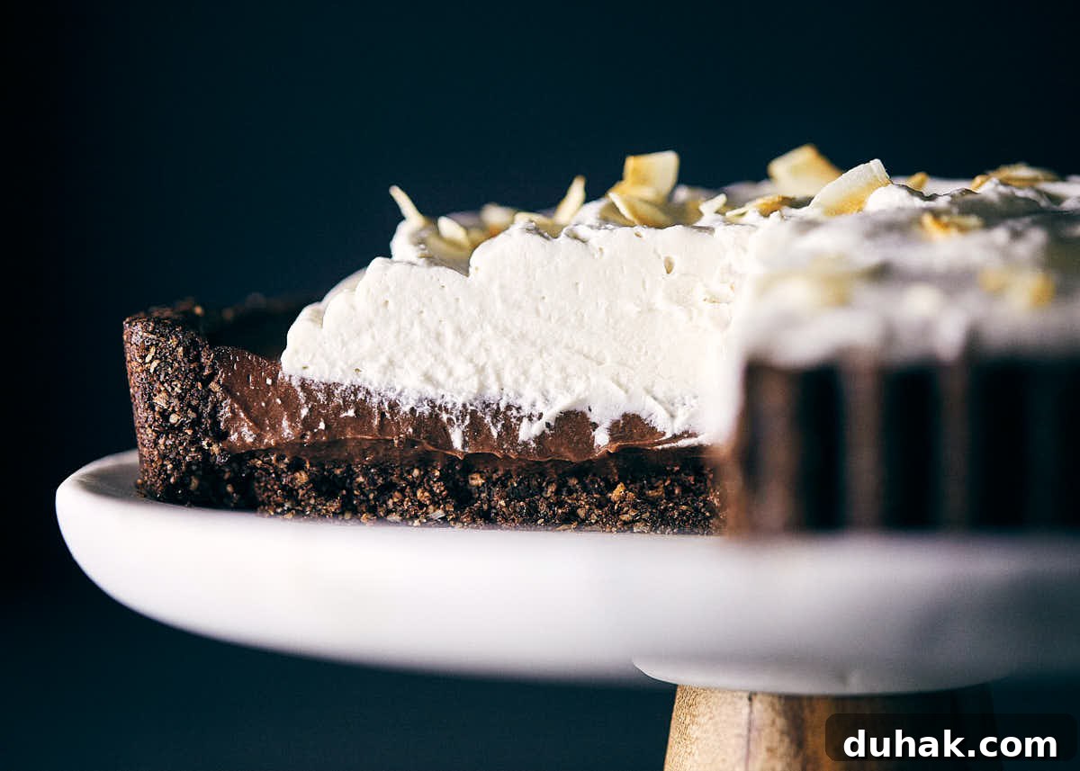 Side view of chocolate coconut cream pie on a cake stand