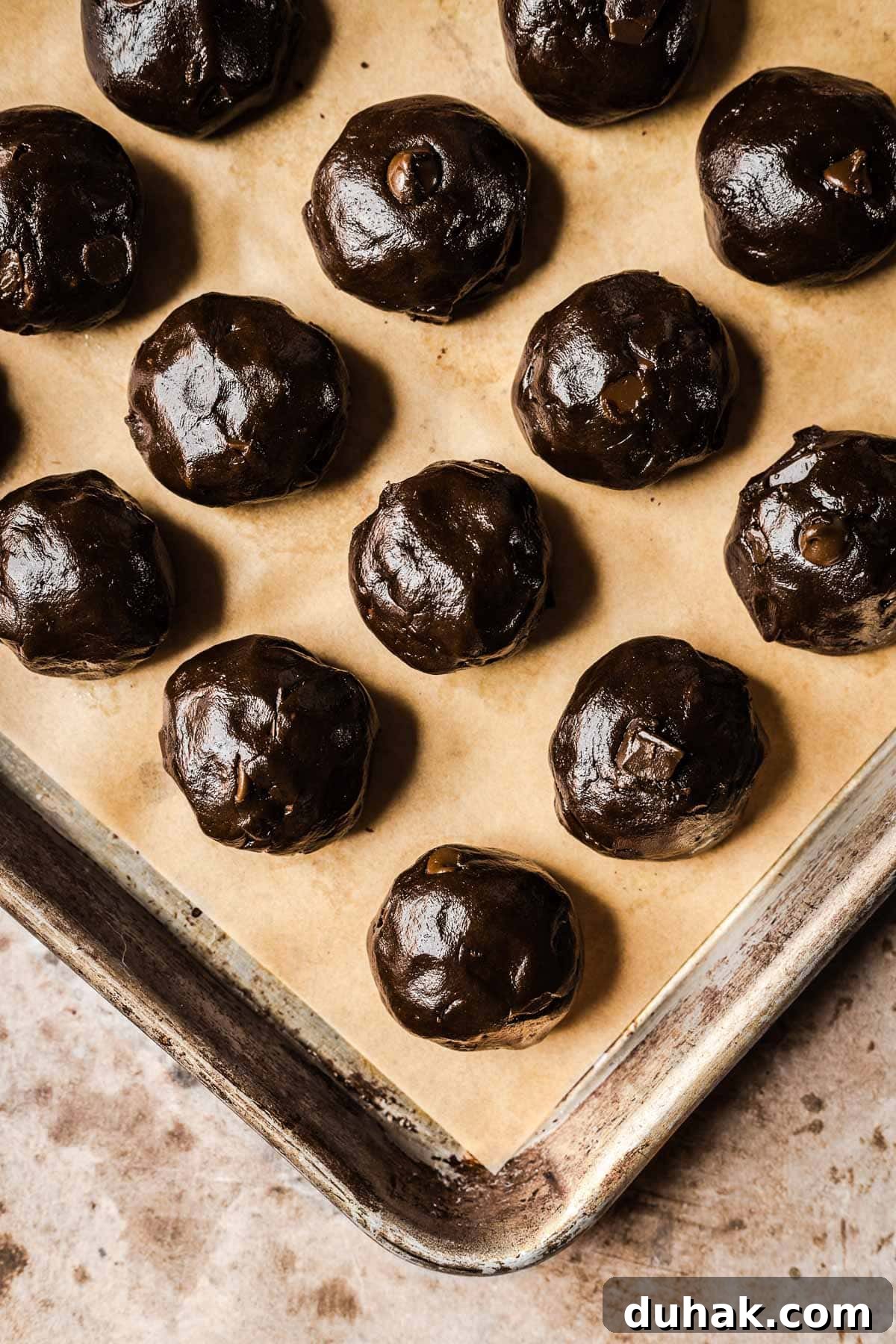 Double Cocoa Chocolate Cookies: Rich, Soft Baked Treats 13 Rolled balls of chocolate cookie dough on a parchment lined baking sheet.