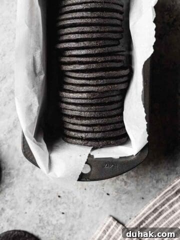 A row of round dark chocolate cookies in a parchment lined pan.