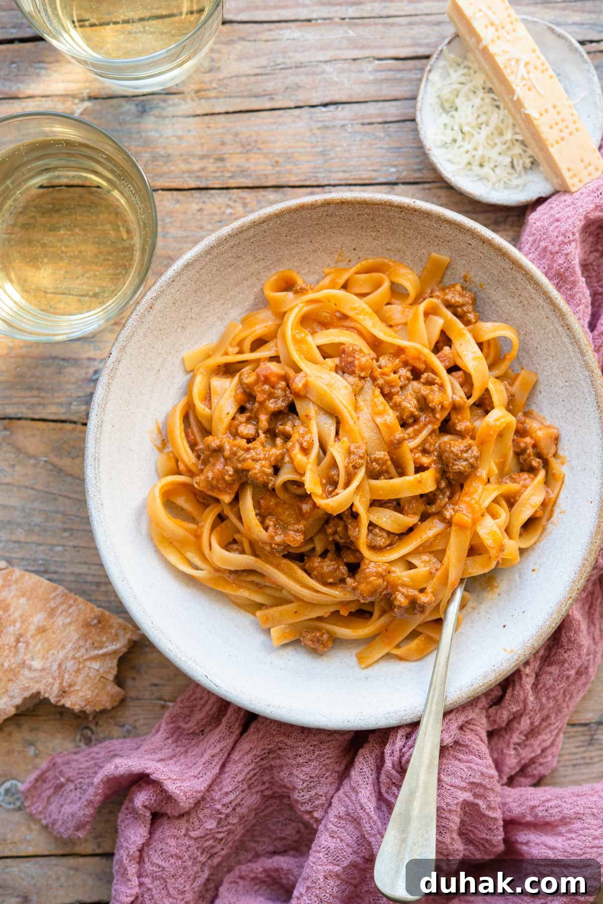 Authentic Ragù alla Bolognese: Classic Italian Meat Sauce Recipe 2 An overhead shot of tagliatelle with bolognese sauce in a bowl with a glass of wine beside it