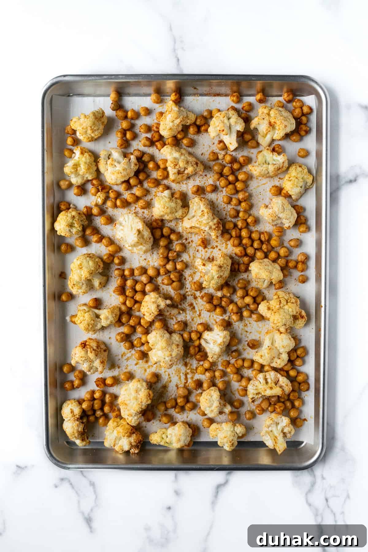 Cauliflower and Chickpeas on a baking sheet ready to be baked.