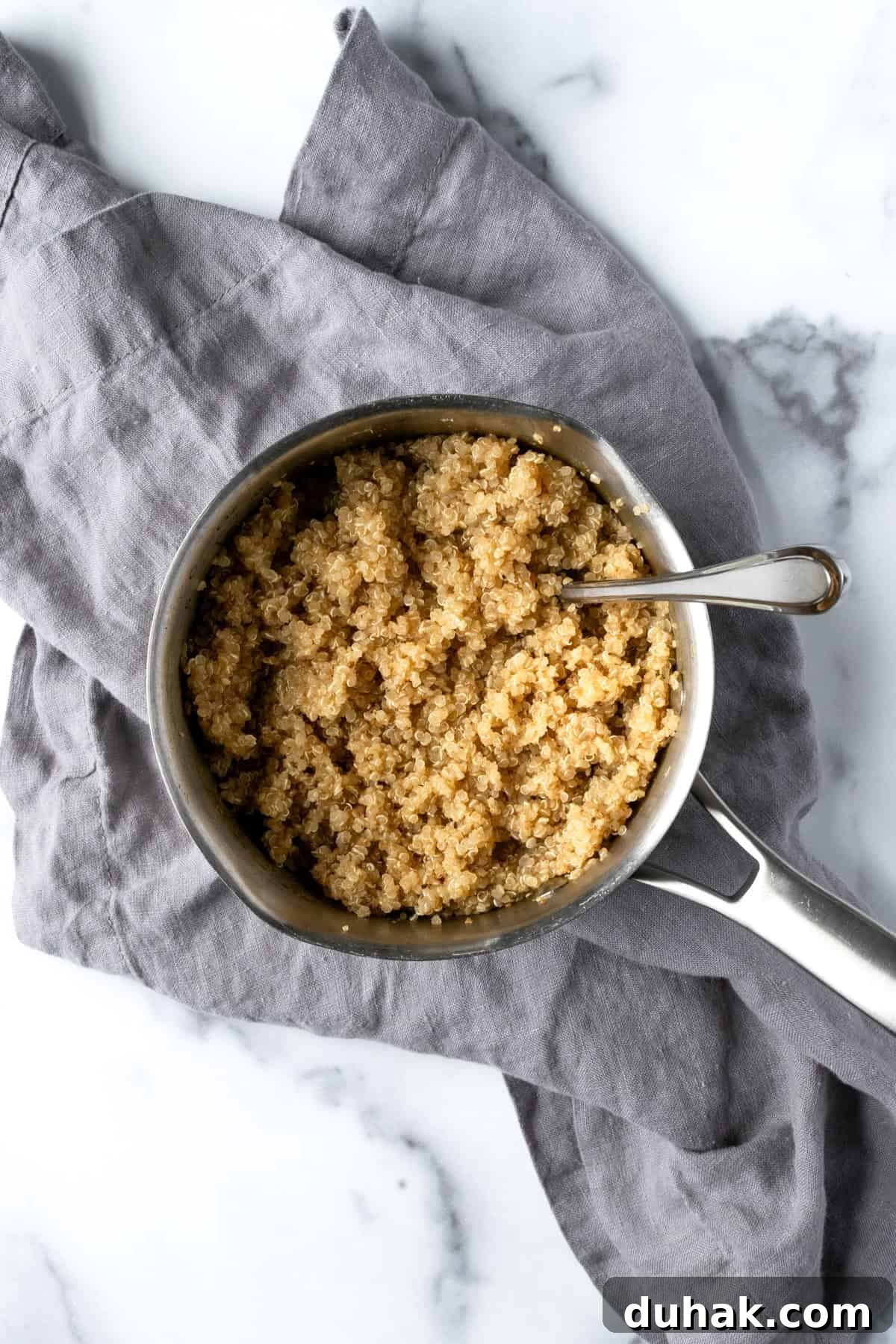 Cooked quinoa in a small pot with a spoon.