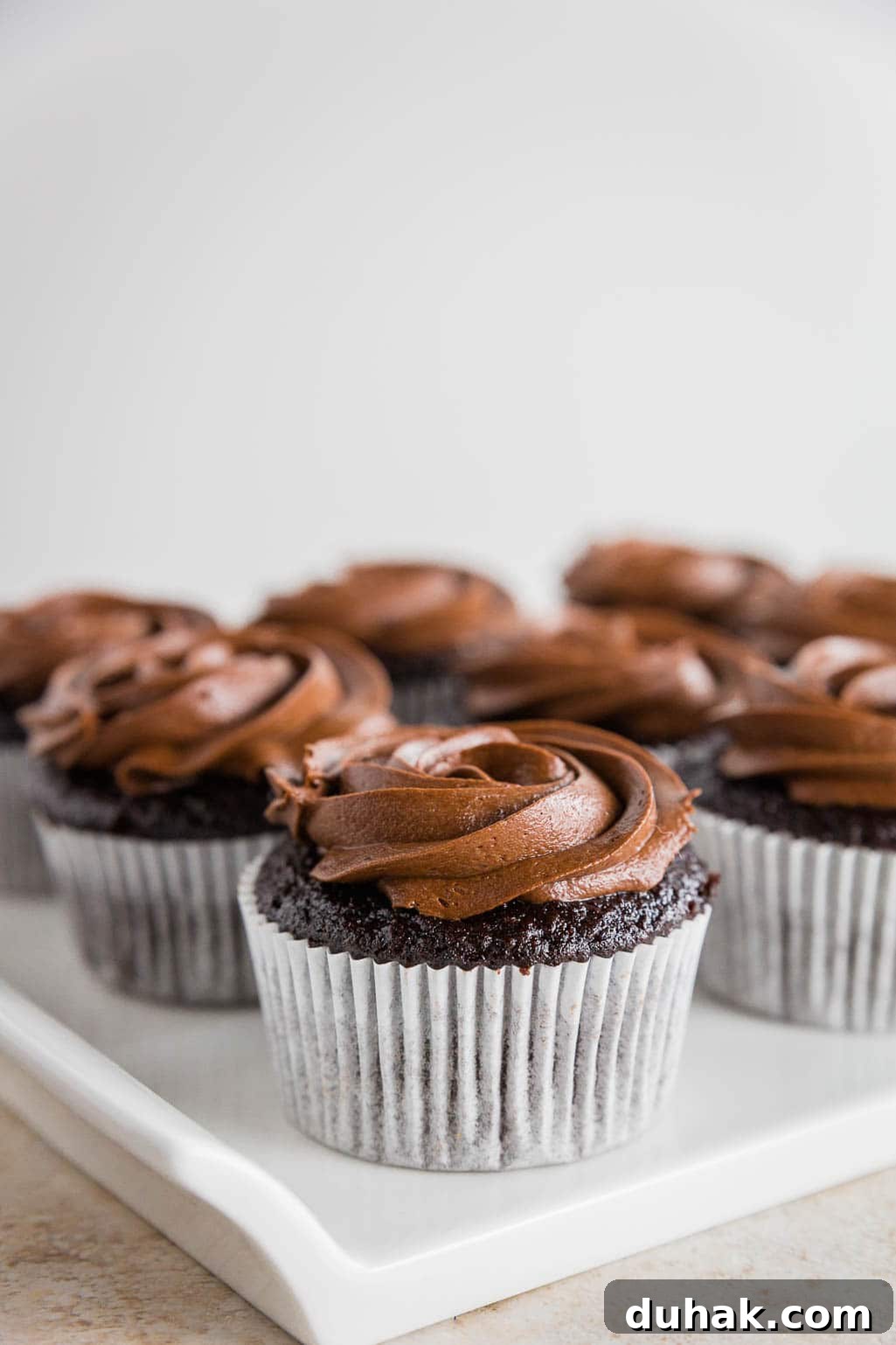 Photo of a gluten-free chocolate cupcake with chocolate frosting in a white cupcake liner.