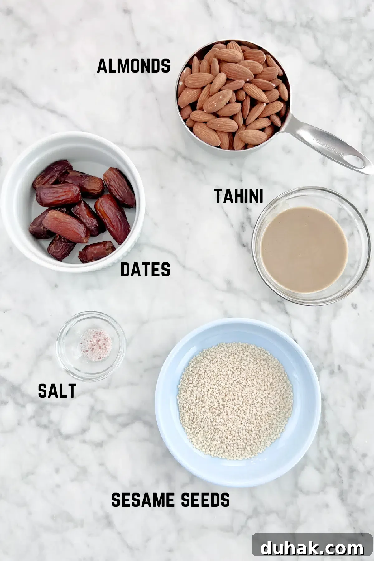 Tahini Almond Date Bites Ingredients measured out to make tahini almond date balls: almonds, dates, tahini, salt, and sesame seeds.