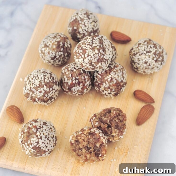 Several small round tahini date bites are arranged on a small bamboo board.