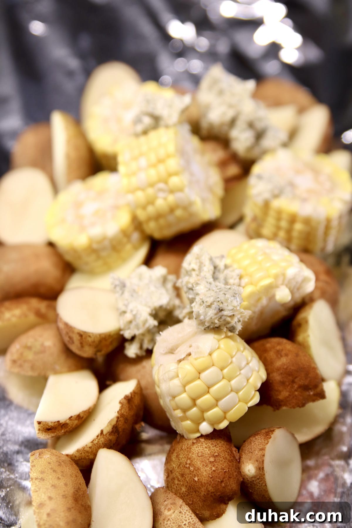 Sliced corn and potatoes on a foil sheet.