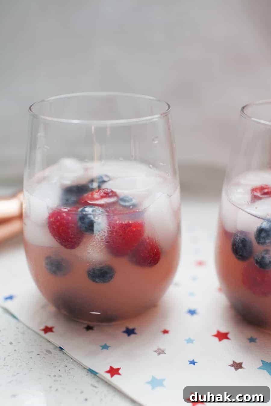 Classic Tequila Soda Recipe: Crisp Low-Calorie Cocktail Guide 6 Two glasses filled with berry-infused White Wine Spritzers sit on a star-patterned napkin.